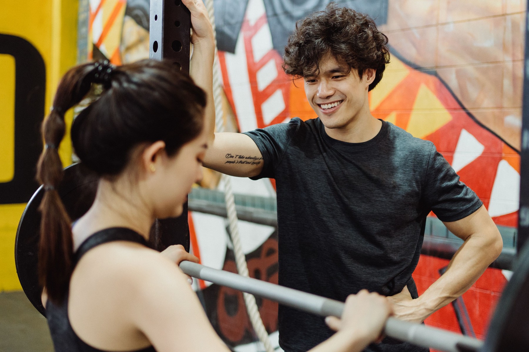 Smiling personal trainer coaching a woman lifting weights in a bright gym studio