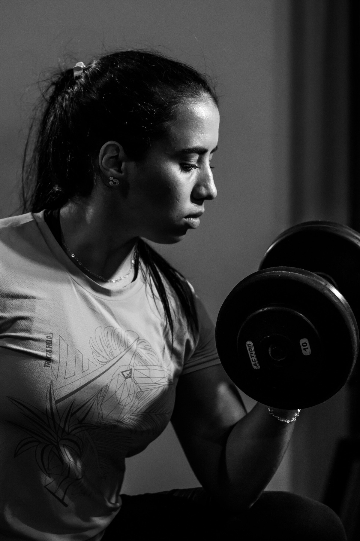 Focused woman lifting a dumbbell in a modern gym