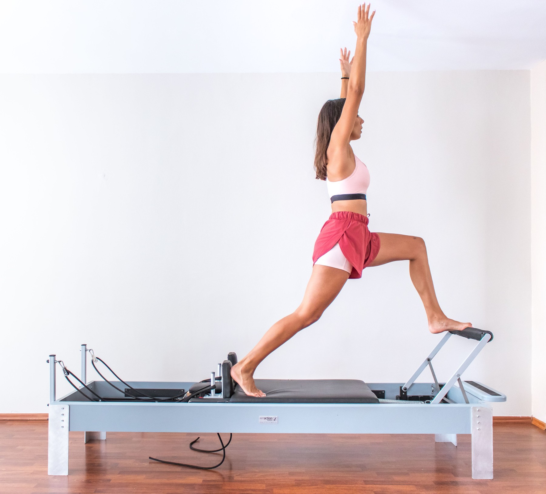 Woman exercising on a Pilates reformer in a bright boutique studio